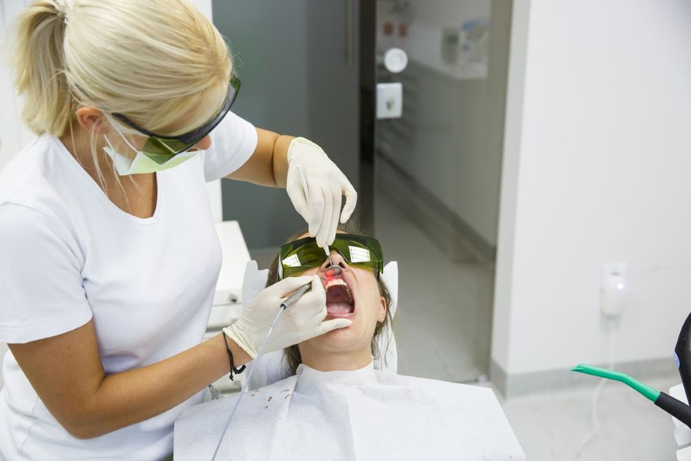 Dental professional performing laser gum treatment on a patient wearing protective eyewear at Oakville Dental